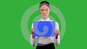 Beautiful, young businesswoman holding a blue clipboard, isolated on green background