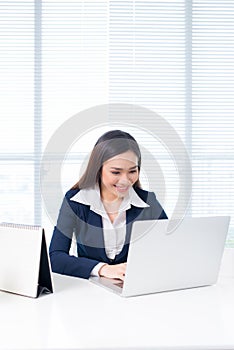 Beautiful young businesswoman sitting at office desk in front of