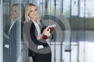 Beautiful young businesswoman smiling and standing with folder in the office. looking at camera. copy space.