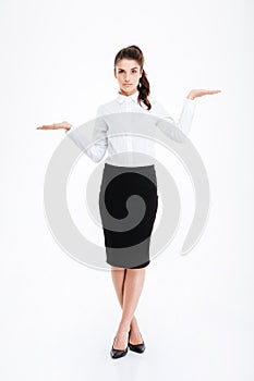 Beautiful young businesswoman standing and holding copyspace on both palms