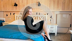 Beautiful young businesswoman taking off shoes in hotel room