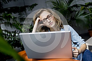 Beautiful young businesswoman using laptop in office with upset experssion