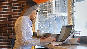 A beautiful young businesswoman works in a cafe and signs contracts