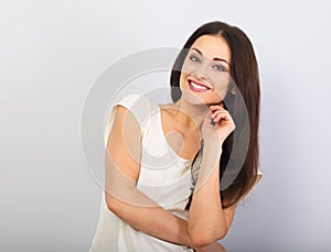 Beautiful young casual cute smiling woman on blue background looking up and thinking. Closeup portrait