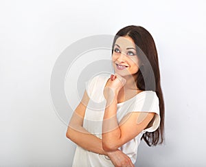 Beautiful young casual cute smiling woman on blue background looking up and thinking. Closeup portrait