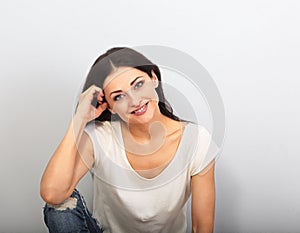 Beautiful young casual cute smiling woman on blue background looking up and thinking sitting in blue jeans. Closeup portrait