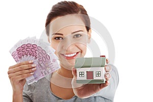 Beautiful young, casual woman holding money and house.