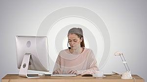Beautiful young casual woman wearing headset working on computer on gradient background.