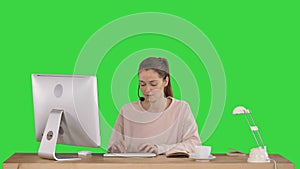 Beautiful young casual woman wearing headset working on computer on a Green Screen, Chroma Key.