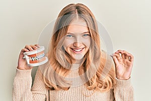 Beautiful young caucasian girl holding invisible aligner orthodontic and braces smiling and laughing hard out loud because funny