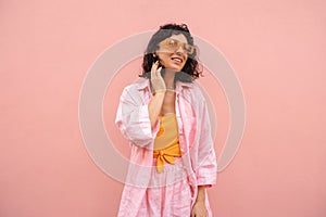 Beautiful young caucasian girl is smiling and averting her gaze posing against pink background. photo