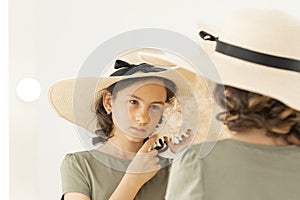 Beautiful young caucasian girl in a straw hat is posing with a white seashell. The girl listens to the sound of the sea.A portrait