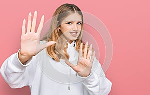 Beautiful young caucasian girl wearing casual sweatshirt afraid and terrified with fear expression stop gesture with hands,