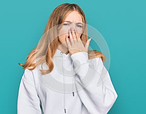 Beautiful young caucasian girl wearing casual sweatshirt bored yawning tired covering mouth with hand