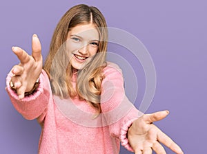 Beautiful young caucasian girl wearing casual winter sweater looking at the camera smiling with open arms for hug