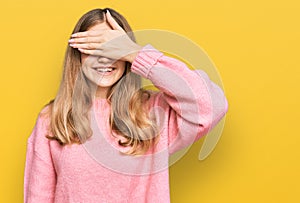 Beautiful young caucasian girl wearing casual winter sweater smiling and laughing with hand on face covering eyes for surprise