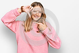 Beautiful young caucasian girl wearing casual winter sweater smiling making frame with hands and fingers with happy face