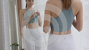 Beautiful young caucasian woman diet thin shape look mirror with waist measuring waist and belly.