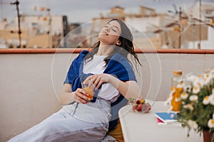 Beautiful young caucasian woman enjoys freshly squeezed orange juice sitting outdoors.