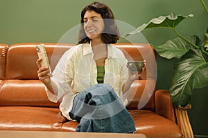 Beautiful young caucasian woman is holding phone and smartphone sitting on sofa in cafe.