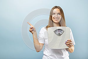 Beautiful young caucasian woman holding weight machine (scale) to balance weight loss