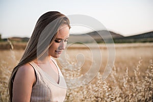 Beautiful young Caucasian woman with long blond hair and sensual appearance against a background of a wheat field