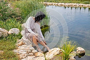 Beautiful young caucasian woman sitting near the lake