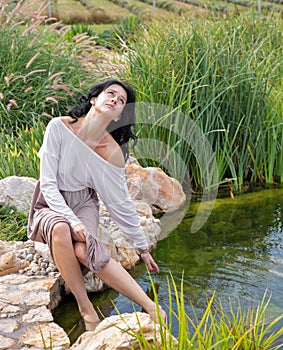Beautiful young caucasian woman sitting near the lake