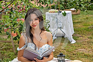 Beautiful young caucasian woman sitting in the orchard garden