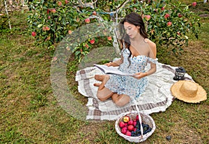 Beautiful young caucasian woman sitting in the orchard garden