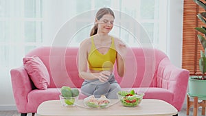 Beautiful young caucasian woman sitting on sofa holding bowl sandwich and salad vegetable for choice eating.