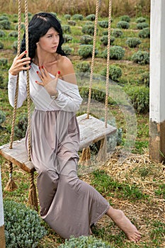 Beautiful young caucasian woman sitting on a wooden swing