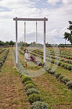 Beautiful young caucasian woman sitting on a wooden swing