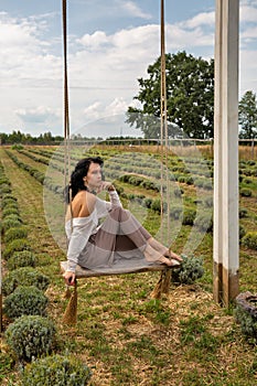 Beautiful young caucasian woman sitting on a wooden swing