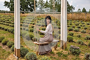 Beautiful young caucasian woman sitting on a wooden swing