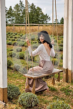 Beautiful young caucasian woman sitting on a wooden swing