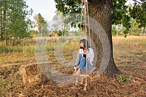 Beautiful young caucasian woman sitting on a wooden swing