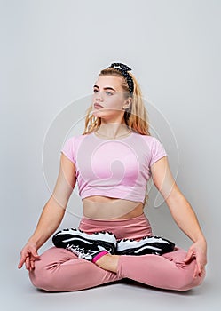 Beautiful young caucasian woman sitting in yoga position and meditating isolated over gray background