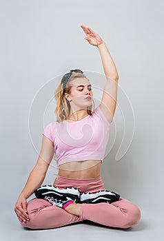 Beautiful young caucasian woman sitting in yoga position and meditating isolated over gray background