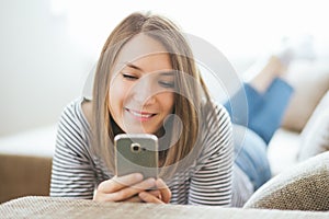 Beautiful young caucasian woman on sofa using cell phone