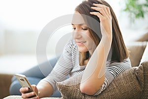 Beautiful young caucasian woman on sofa using cell phone