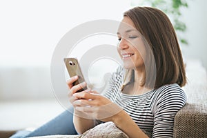 Beautiful young caucasian woman on sofa using cell phone