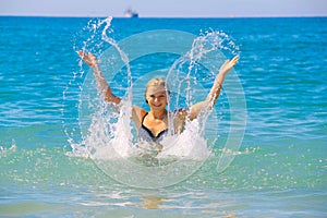 Beautiful young caucasian woman splashing the water in the sea on Summer day.