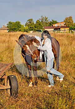 Beautiful young caucasian woman standing near the horse