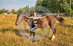 Beautiful young caucasian woman standing near the horse