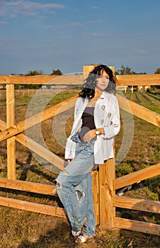 Beautiful young caucasian woman standing at the ranch gate