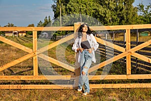 Beautiful young caucasian woman standing at the ranch gate