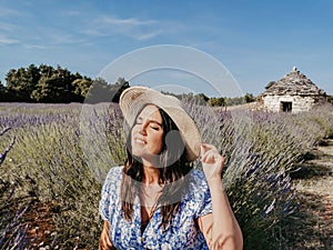 Beautiful young Caucasian woman in a straw hat posing in a lavender field