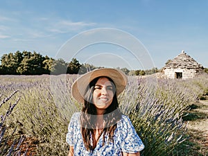 Beautiful young Caucasian woman in a straw hat posing in a lavender field