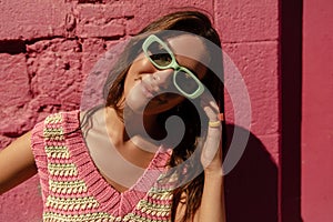 Beautiful young caucasian woman in stylish sunglasses looking posing at camera during sunny morning.
